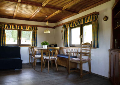 Gemütlicher Essbereich im Ferienhaus Meyer (Westerwald) mit hölzerner Eckbank, rustikaler Deckenverkleidung und hellem Fenster