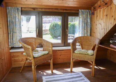 Gemütliche Sitzecke mit zwei Korbsesseln vor dem Fenster mit Blick ins grüne im Obergeschoss von Ferienhaus Meyer im Westerwald.